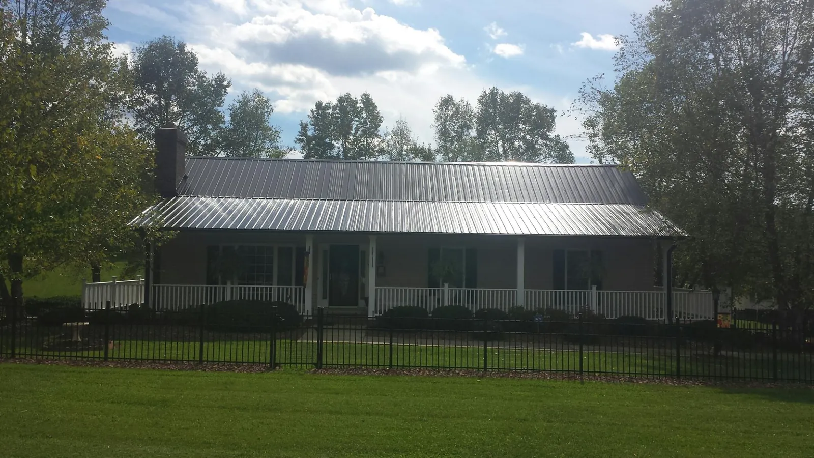 Gray metal roof on a brick ranch with a full width front porch — Gutter Guard Installation work by our crew in Sheffield